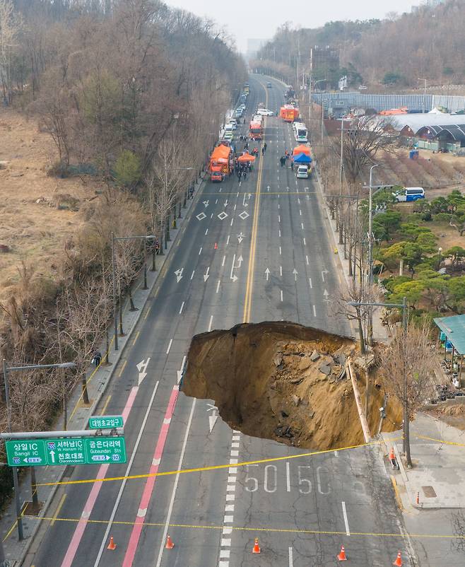 25일 오전 서울 강동구 대명초교입구 교차로 인근에서 대형 싱크홀 모습.  소방과 경찰이 차량 통행을 통제하고 있다. /장련성 기자