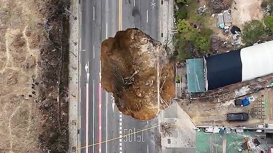 25일 강동구 대명초등학교 도로에서 전날 발생한 대형 땅꺼짐 현장의 모습. 전날 오후 명일동 대명초등학교 인근 사거리에서 발생한 지름 20ｍ, 깊이 18ｍ가량의 대형 싱크홀(땅꺼짐)에 오토바이 운전자 1명이 빠져 실종됐다. 드론 영상 캡처