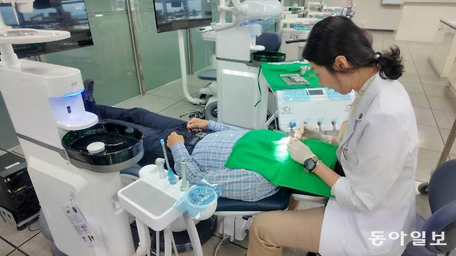 한지형 수원과학대 치위생과 교수가 치과 진료대 의자(유니트 체어)에 누운 본보 기자의 치아를 살피면서 치석을 제거하고 있다. 이진한 의학전문기자·의사 likeday@donga.com