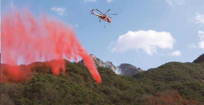 헬리콥터를 이용해 산불지연제를 살포하고 있다. 산불지연제는 원래 무색이나 살포한 곳을 구별하기 위해 분홍색, 붉은색 등 색소를 섞어 사용한다. 국립산림과학원 제공