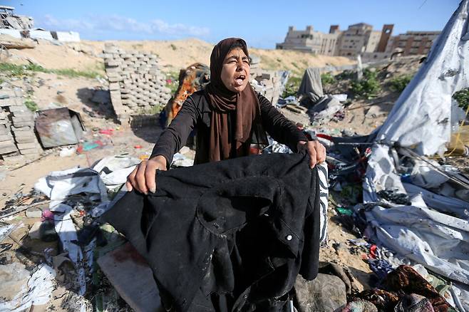 한 팔레스타인 여성이 2025년 3월19일(현지시각) 팔레스타인 가자지구 남부에 있는 도시 칸유니스에서 이스라엘군의 무차별 폭격에 의해 무너진 천막 현장을 보고 있다. 로이터 연합뉴스