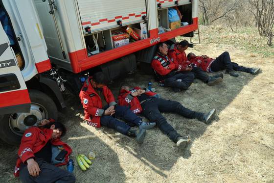 Exhausted firefighters take a nap in the shade of a fire truck in Sancheong County, South Gyeongsang, on March 26. [SANCHEONG COUNTY]
