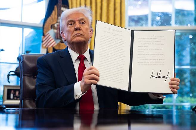 도널드 트럼프 미국 대통령이 26일(현지시간) 모든 수입 자동차에 25%의 관세를 부과하는 내용의 포고문에 서명한 뒤 취재진에게 보여주고 있다. 연합뉴스