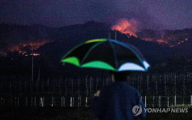 산불 잠재우기에 턱없이 부족한 비 (영양=연합뉴스) 윤관식 기자 = 27일 경북 영양군 입암면 노달리 마을에서 한 주민이 우산을 쓰고 산불 상황을 살펴보고 있다.
    이날 오후 7시께 영양군에는 굵은 빗방울이 잠시 떨어졌다. 2025.3.27 psik@yna.co.kr