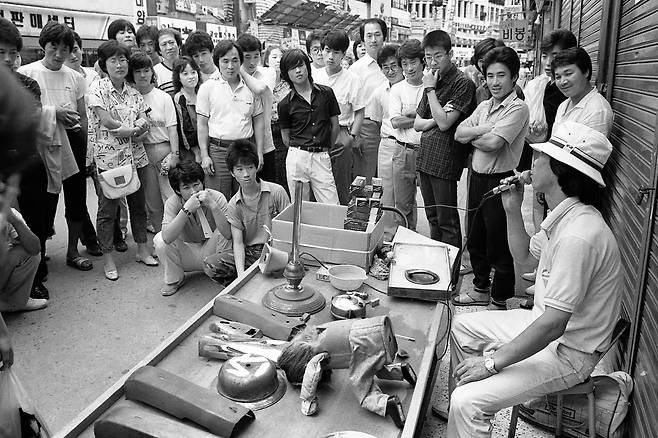1985년 부산 광복동. 거리의 약장수가 인사하는 로봇 장난감을 켜놓고 행인들을 모으고 있다. /사진가 문진우