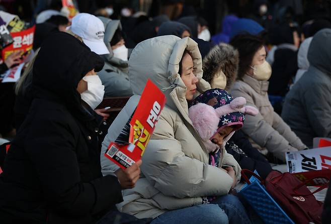 ‘윤석열 즉각 퇴진! 사회대개혁! 범시민대행진 17차’가 서울 종로구 광화문 일대에서 열린 29일 오후 두꺼운 외투를 입은 참석자가 아이를 품에 안고 발언을 듣고 있다. 김혜윤 기자 unique@hani.co.kr