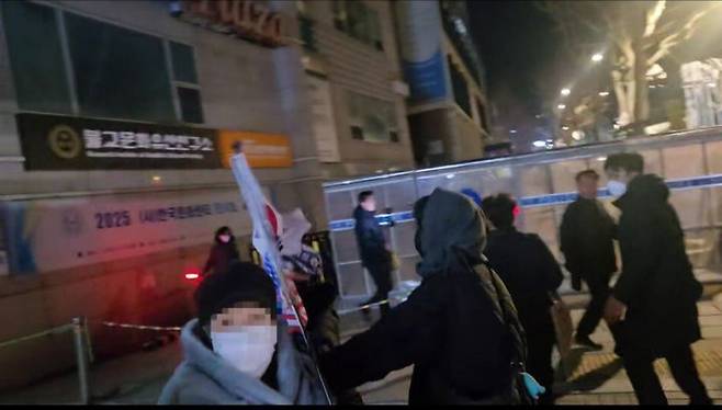 [서울=뉴시스] 조성하기자 =서울 종로구 헌법재판소 인근에서 파란 색 모자를 쓴 여성이 탄핵 반대 집회 측 참가자를 때리는 모습(시민제공). 2025.03.29. create@newsis.com *재판매 및 DB 금지