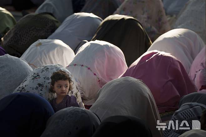 [쿠알라룸푸르=AP/뉴시스] 31일(현지 시간) 말레이시아 쿠알라룸푸르의 국립 모스크 마스지드 느라그에서 한 소녀가 이드 알피트르 기도를 올리는 사람들을 지켜보고 있다. 2025.03.31.