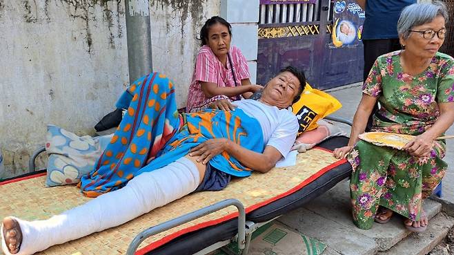 미얀마 만달레이에서 무너진 집 잔해에 깔려 다친 아웅수웨이윙(61)씨가 입원하지 못하고 집 앞에서 침상을 깔고 노숙하고 있다. 연합뉴스