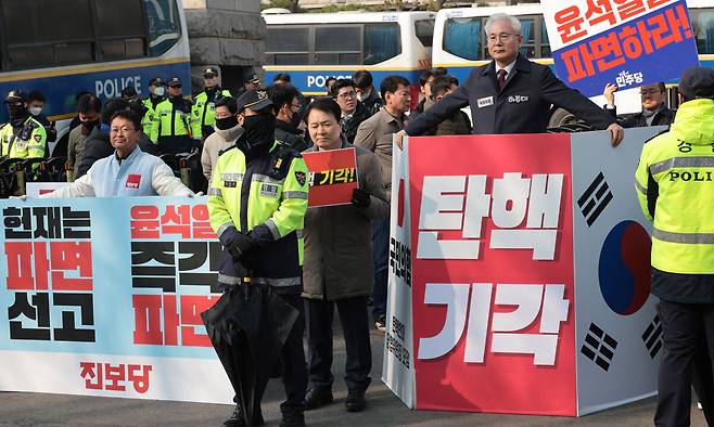 윤석열 대통령 탄핵심판 심리가 4월로 넘어온 1일 서울 종로구 헌법재판소 앞에서 국민의힘과 더불어민주당, 진보당 관계자들이 손팻말을 들고 1인 시위를 하고 있다. 연합뉴스