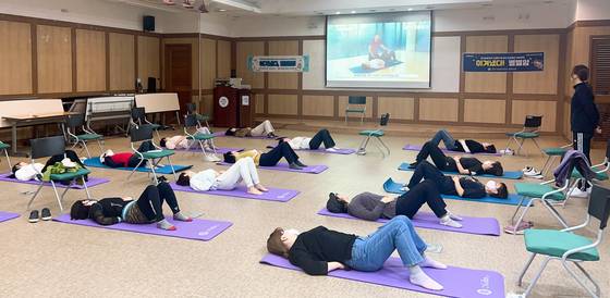 암 생존자들이 국립암센터 암생존자통합지지센터에서 물리치료사의 지도를 받으면서 팔을 비롯한 상지근육 기능 개선 운동을 하고 있다. 사진 국립암센터