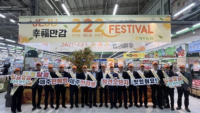 고양유통센터에 제주 감귤 홍보 사절단이 총출동했다. ‘행복만감 페스티벌’ 현수막 아래 주황색 모자를 쓴 관계자들이 줄지어 서 있다. (제주농협 제공)