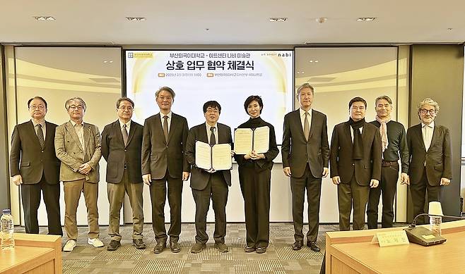 부산외대 장순흥 총장(왼쪽에서 다섯 번째)과 아트센터 나비 미술관 노소영 관장(오른쪽에서 다섯 번째)이 ‘EAST MEETS EAST’ 국제 컨퍼런스 공동 개최를 위한 협약서를 들고 기념 촬영을 하고 있다. 사진=부산외대 제공