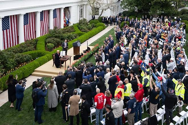 2일(현지시간) 워싱턴DC 백악관 로즈가든에서 열린 ‘미국을 다시 부유하게(Make America Wealthy Again)’ 행사에서 도널드 트럼프 미국 대통령(연단 왼쪽)이 정·관계 인사들과 지지자들의 환호를 받으며 자신이 서명한 상호관세 행정명령을 들어 보이고 있다. [AFP=연합뉴스]