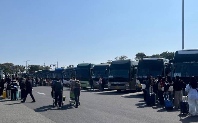 제주국제공항 밖, 전세버스들이 길게 줄지어 수학여행을 온 학생들을 기다리고 있다. 학생들은 반별로 모여 탑승 순서를 기다리는 중이다. (제주도관광협회 제공)