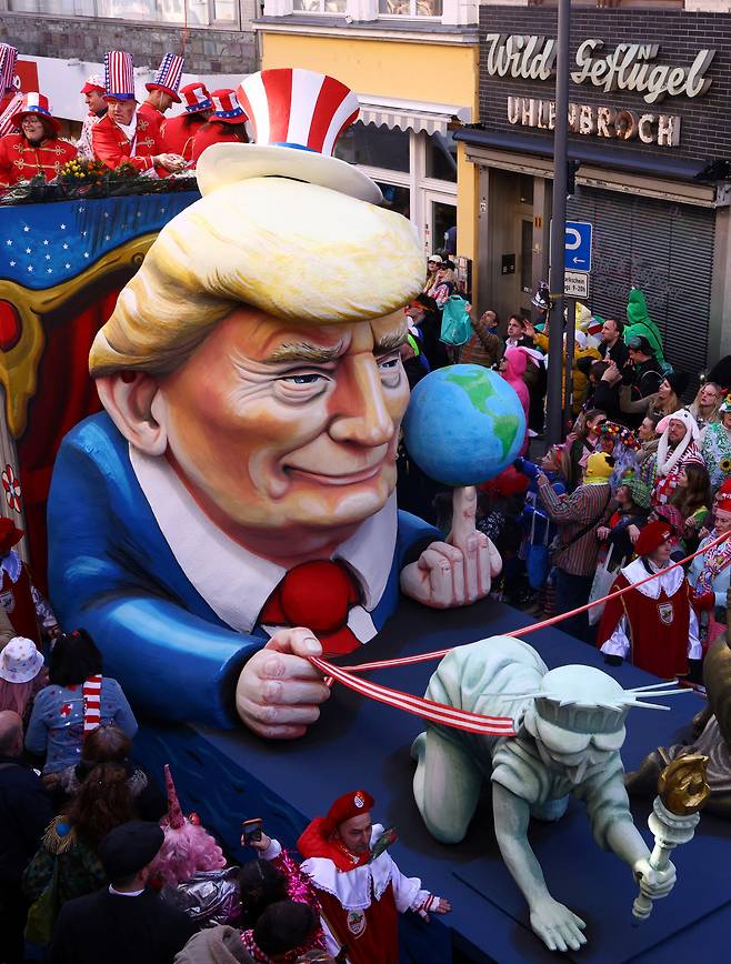 지난 3월 3일 독일 쾰른에서 열린 전통적인 ‘로젠몬탁(Rosenmontag·장미 월요일)’ 카니발 퍼레이드에 미국 대통령 도널드 트럼프가 자유의 여신상과 정의의 여신을 목줄에 묶어 끌고 있는 모습을 형상화한 카니발 퍼레이드 차량이 행진하고 있다. 로이터