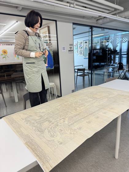 Sohee Myers, a student at Jinchae Lab, works on her jinchae, or silk painting, at the studio in southern Seoul. [JINCHAE LAB]