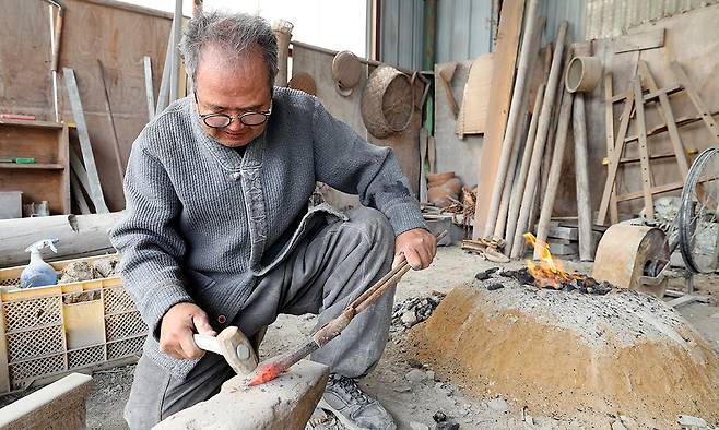 오랜 사용으로 무뎌진 조각정을 불에 달궈 뾰족하게 다시 만들고 있는 고석산 석장.