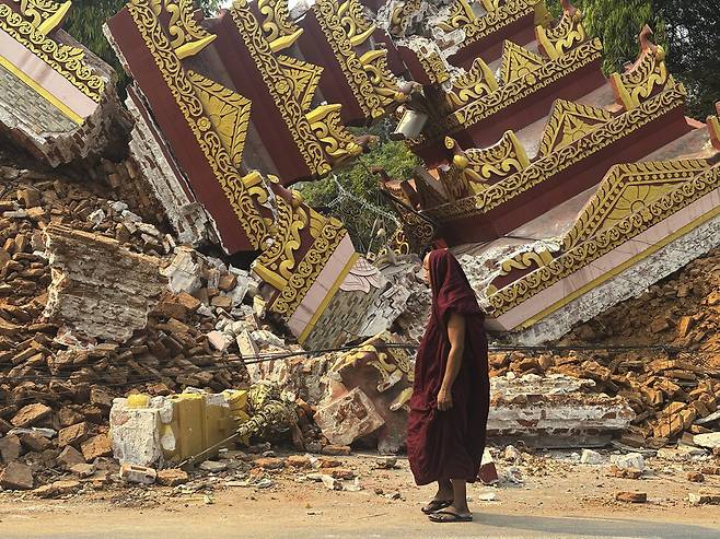 2025년 3월30일 미얀마 중부 만달레이에서 한 승려가 강진으로 무너진 불교 사원 앞을 지나고 있다. AP 연합뉴스