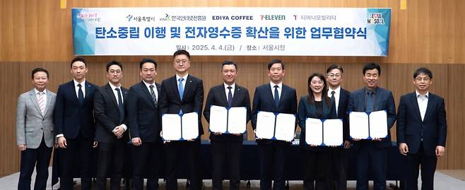 지난 4일 서울시청 서소문청사에서 열린 '탄소중립 이행 및 전자영수증 확산을 위한 업무협약식'에서 조규동 이디야 대표(왼쪽 앞줄 다섯 번째부터), 김홍철 코리아세븐 대표, 권민 서울시 기후환경본부장, 김정희 한국인터넷진흥원(KISA) 디지털안전지원본부장, 조동욱 티머니모빌리티 대표가 기념촬영하고 있다./사진=한국인터넷진흥원(KISA)