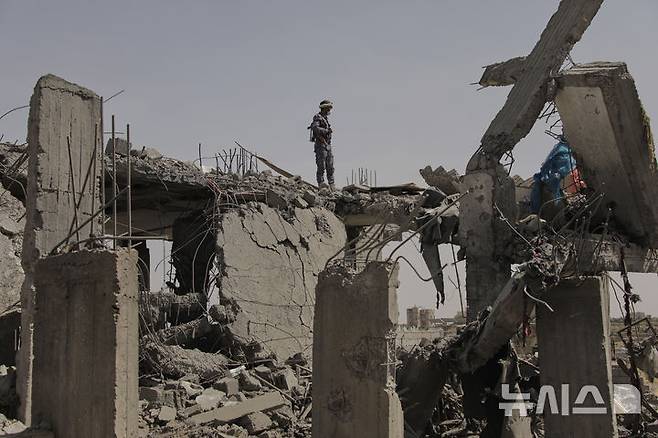 [사나(예멘)=AP/뉴시스] = 예멘의 수도 사나에서 4월 7일 후티군 보안군 장교 한 명이 전날의 미군 폭격으로 무너진 건물 잔해를 조사하고 있다. 2025. 04. 08.