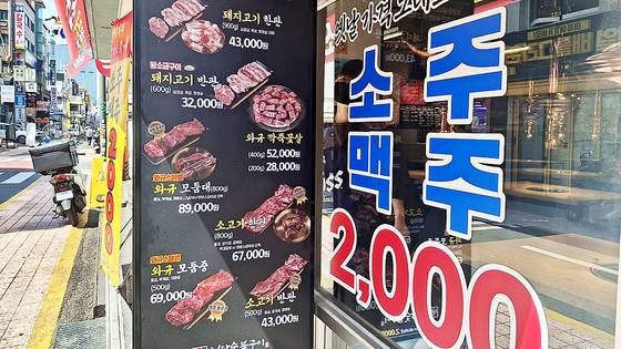 8일 서울 건대입구역 부근의 한 식당이 소주, 맥주를 ″옛날 가격 그대로″ 2000원에 판매한다고 유리벽에 쓴 모습. 불경기에 소비심리가 위축되자 자영업자들은 술값을 낮춰 생존을 모색하고 있다. 김성진 기자