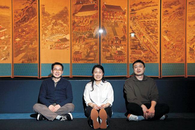 보존처리를 마친 후 전시된 ‘평안감사도과급제자환영도’ 앞에 앉은 한종철(왼쪽부터) 수석연구원, 남유미 보존연구실장, 강규성 책임연구원. 그림이 지워져 있던 오른쪽에서 6번째 화폭은 보존처리를 마친 후에도 비워져 있다. 남 실장은 “보존 전문가는 화가가 아니기에 원본에서 한 획도 마음대로 추가할 수 없다”고 설명했다.  문호남 기자