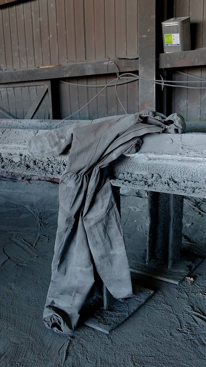 경기도 화성의 한 공장 구석에 외국인 노동자가 입던 옷을 벗어 놓았다. 사진가는 옷이 걸쳐진 모습이 쓰러져 지친 외국인 노동자처럼 보였다고 했다.  2015년/ 사진가 심학철