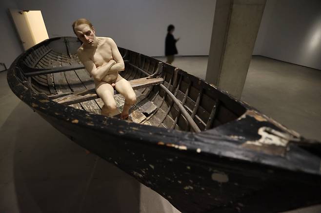 '배에 탄 남자'(2002)가 전시된 모습. 팔을 모아 벗은 몸을 간신히 가린 남자가 보트의 뱃머리에 앉아 무언가를 의심하는 듯한 눈길을 보내고 있다. 159 × 138 × 429cm. 개인 소장. /연합뉴스