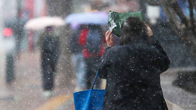 강풍을 동반한 눈비가 갑작스럽게 내린 13일 오후 서울 중구 덕수궁 인근에서 시민들이 발걸음을 재촉하고 있다. /박성원 기자