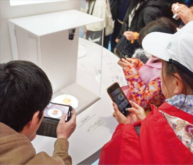 < 만능세포로 만든 심근 시트 > 14일 일본 바이오기업 쿠오립스가 오사카·간사이 엑스포 ‘오사카 헬스케어관’에 전시한 ‘심근 시트’를 관람객들이 보고 있다. 쿠오립스는 유도만능줄기세포(iPSC)로 키운 심장근육 세포를 가공해 만든 이 심근 시트를 지난 8일 일본 후생노동성에 제조·판매 신청했다.  김일규 특파원