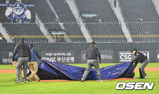 [OSEN=부산, 이석우 기자] 12일 부산 사직야구장에서 2025 신한 SOL 뱅크 KBO 리그 롯데 자이언츠와 NC 다이노스의 경기가 열렸다. 주말 3연전 동안 NC 다이노스가 창원NC파크 대신 사직야구장을 홈구장으로 사용한다. 홈팀 NC는 신민혁, 방문팀 롯데는 데이비슨이 선발 출전했다.심판들과 관계자들이 비가 오는 중에도 경기 재개를 위해 방수포를 치우고 있다. 2025.04.12 / foto0307@osen.co.kr
