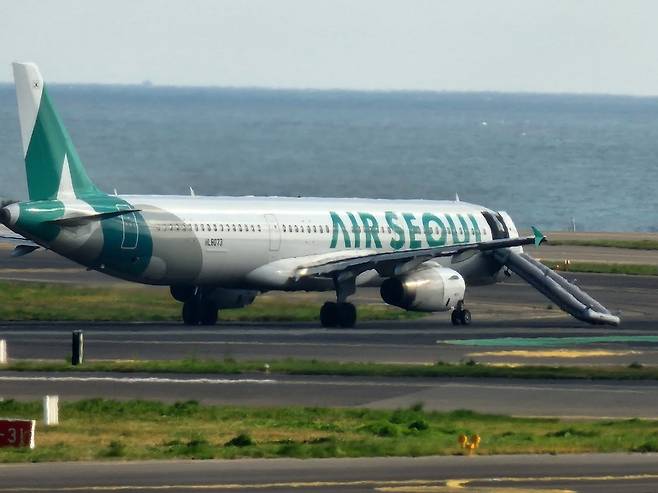 김포행 에어서울 항공기가 15일 비상문이 열리고 비상 탈출 슬라이드가 펼쳐진 채 제주국제공항&nbsp;활주로에 서 있다. 한 승객이 비상문을 허가없이 개방한 것으로 조사됐다. 제주=뉴스1