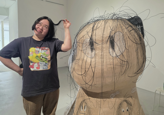 신민 작가가 자신의 작품 '민정' 옆에서 익살스러운 포즈를 취해보고 있다. 김경미 기자