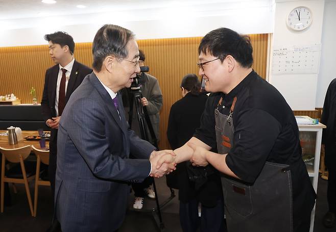 한덕수 대통령 권한대행 국무총리가 16일 울산 중구에서 결식 아동들에게 점심 식사를 무료로 제공해온 식당 ‘뚠뚠이 돈가스’를 찾아 사장과 악수하고 있다. /뉴시스