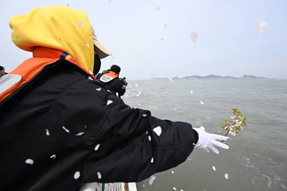 세월호 참사 11주기인 16일 오전 전남 진도군 맹골수도에서 열린 선상추모식 중 세월호 참사 유족이 희생자를 기리며 벚꽃을 바다에 던지고 있다. 이 꽃은 희생자들이 다닌 단원고등학교 교정에 핀 벚꽃이다. 뉴시스