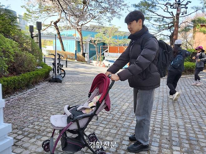 경향신문 김태욱 기자가 15일 서울 서대문구 안산 벚꽃길에서 유아치를  밀며 이동하고 있다.  유아차에는 9㎏ 아령 원판과 아이 모양 인형을 실었다. 오동욱 기자