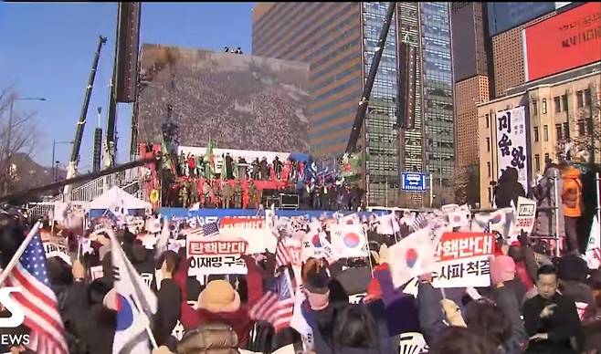 서울 광화문 일대에서 열린 집회 현장. 탄핵 반대를 외치는 참가자들이 윤석열 전 대통령의 이름을 함께 외치며 태극기와 성조기를 흔들고 있다.