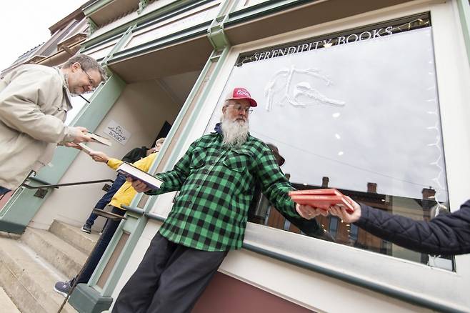 미국 미시간주 작은 마을 첼시의 동네 책방 세렌디피티북스(Serendipity Books)의 지난 13일 이삿날 봉사자들이 인간띠를 만들어 한 블록 떨어진 새 매장으로 이사를 돕는 장면. AP 연합뉴스