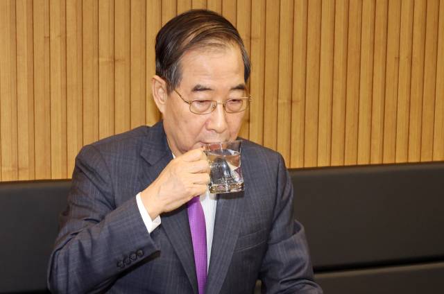 한덕수 대통령 권한대행 국무총리가 16일 결식 아동들에게 무료 점심을 제공해온 울산 뚠뚠이 돈가스에서 사장과 직원들을 격려한 후 물을 마시고 있다.연합뉴스