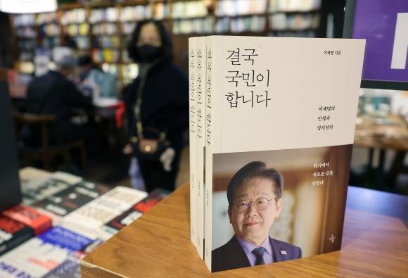 이재명 대선후보 ‘결국 국민이 합니다’ 출간 - 14일 서울 종로구 교보문고에서 직원이 이재명 전 더불어민주당 대표의 신간 ‘결국 국민이 합니다’가 진열되어 있다. 책은 지난해 12월 3일 비상계엄부터 윤석열 대통령 탄핵소추안 가결, 헌재의 파면 선고까지 숨 가빴던 순간들을 담아냈고 지난해 1월 예상치 못한 피습 이야기, ‘소년공’ 출신 이재명의 인생 항로와 정치 역정, 당대표직에 대한 소회, ‘정치란 무엇인가’라는 근본적인 물음 등도 포함됐다.   2025.4.14/뉴스1
