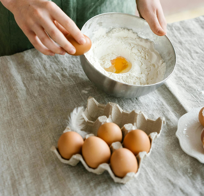 밀가루 반죽에 계란을 깨서 넣고 있는 모습