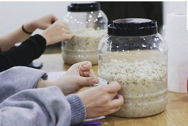 Participants of Seoul's hands-on makgeolli class Suguk attach labels to their fermentation pots containing the mixed makgeolli ingredients after the session. (Suguk)