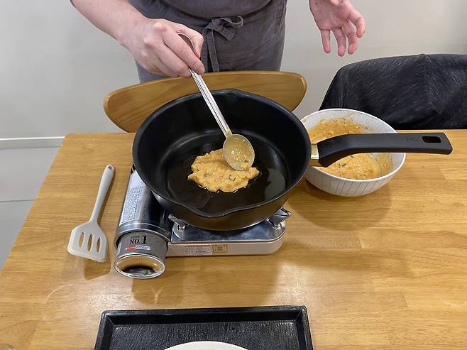 Gilles Landric, a participant in the makgeolli-making class at Suguk, makes kimchijeon during Monday's session. (Lim Jae-seong/The Korea Herald)