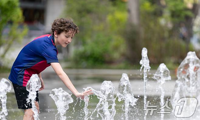 서울 낮 최고기온이 26도를 기록하는 등 초여름 날씨를 보인 21일 서울 세종대로 광화문광장 터널분수에서 외국인 어린이가 더위를 식히고 있다. 2025.4.21/뉴스1 ⓒ News1 이승배 기자