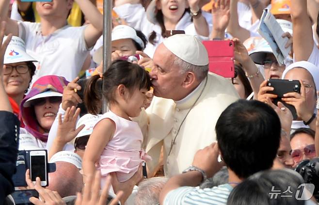 프란치스코 교황이  지난 2014년 8월16일 서울 광화문 광장에서 열린 '윤지충 바오로와 동료 순교자 123위 시복 미사'를 집전하기위해 오픈카를 타고 이동하며 언린이 이마에 뽀뽀를 하고 있다. (뉴스1 DB)