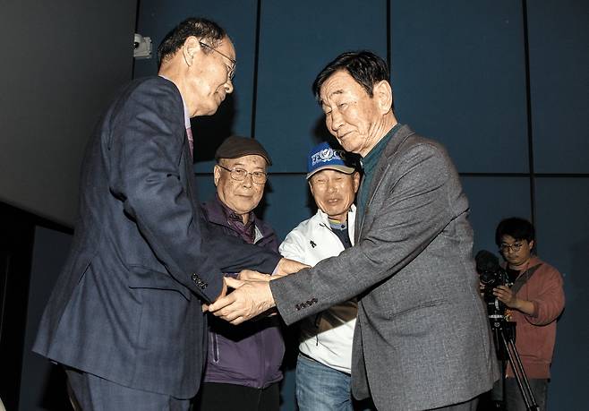 20일 강원도 영월군 영월시네마에서 열린 다큐멘터리 영화 ‘1980 사북’ 특별상영회에 1980년 ‘사북사건’ 당시 대치했던 진문규(맨 왼쪽)·최병주(왼쪽에서 두 번째)·이종환(오른쪽에서 두 번째) 전 영월경찰서 순경과 이원갑 사북항쟁동지회 명예회장이 손을 마주잡고 화해하고 있다./조인원 기자