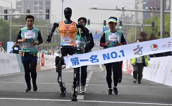 19일 중국 베이징에서 열린 ‘휴머노이드 로봇’ 하프마라톤 대회에서 1위를 차지한 ‘톈궁 울트라’가 2시간 40분 42초의 기록으로 결승선을 통과하고 있다. 베이징=신화 뉴시스