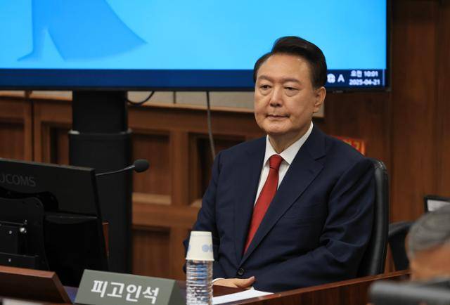 윤석열 전 대통령이 21일 서울 서초동 서울중앙지법에서 열린 내란 우두머리 혐의 형사재판 두 번째 공판에 출석해 피고인석에 착석해 있다. 사진공동취재단