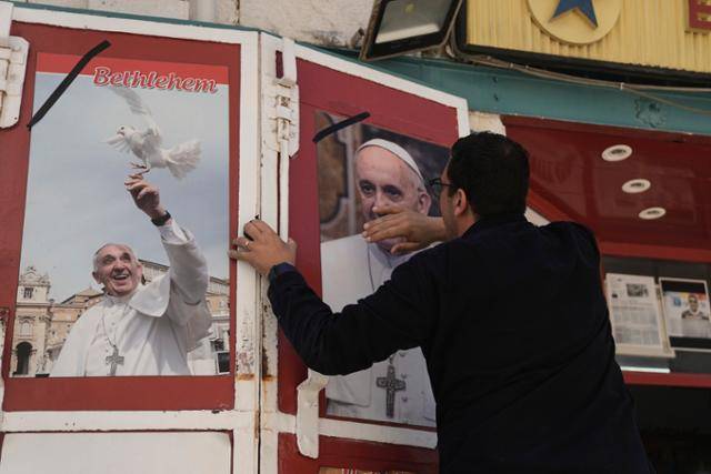 팔레스타인 서안지구의 베들레햄에서 한 상인이 21일 선종한 프란치스코 교황 사진 주위로 검은 리본을 두르고 있다. 베들레햄은 예수 그리스도가 탄생한 가톨릭 성지다. 베들레=AP 연합뉴스